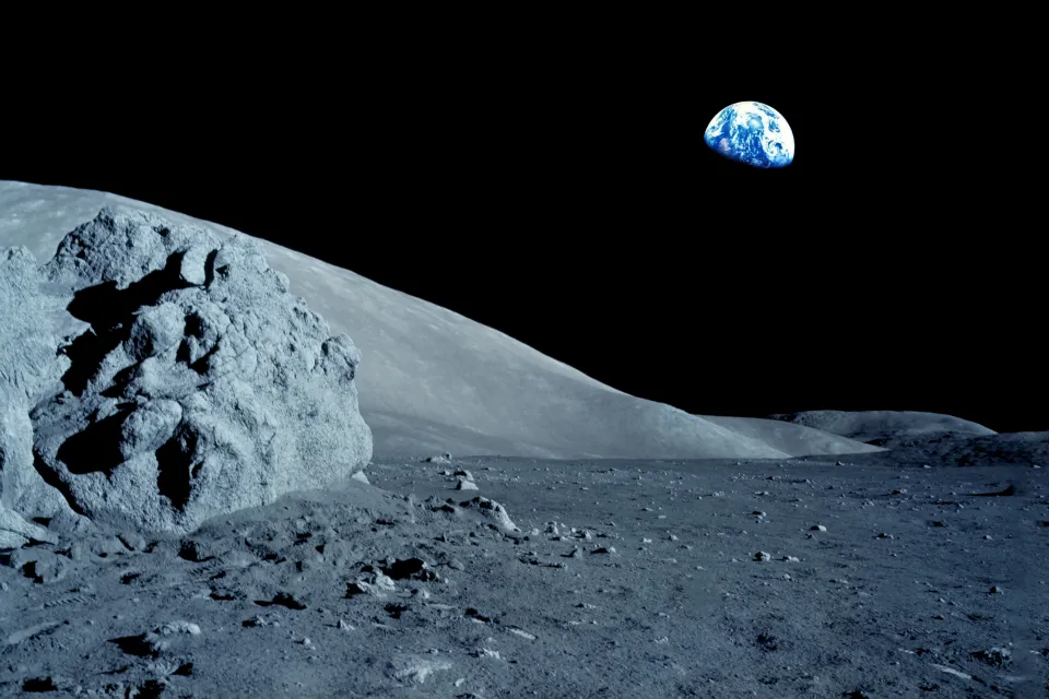 Gray moon surface with black sky and Earth in the background.